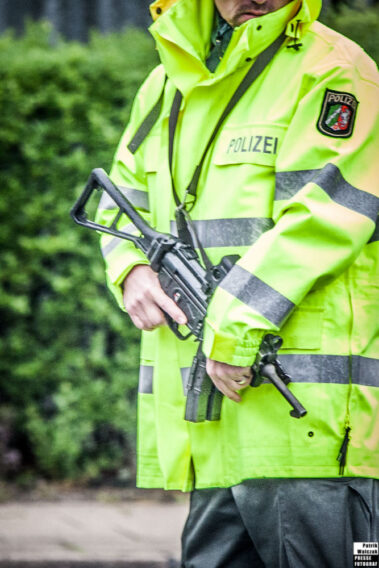 Polizei mit einer Maschinenpistole als Bewaffnung vor einer Party des Bandidos MC.